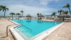 A rectangular swimming pool with a white border and a blue edge, surrounded by a white fence and palm trees. - Discover the Epitome of Waterfront Living in this Stunning condo on Isla del Sol!~ (St Petersburg)
