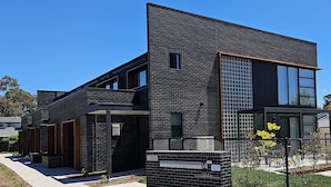A modern two-story building with a brick facade, large windows, and a visible mailbox.