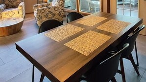 Un comedor con una mesa de madera, sillas negras y un ventilador de techo.