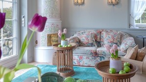 Sala de estar com sofá estampado, lustre e vista para o exterior.