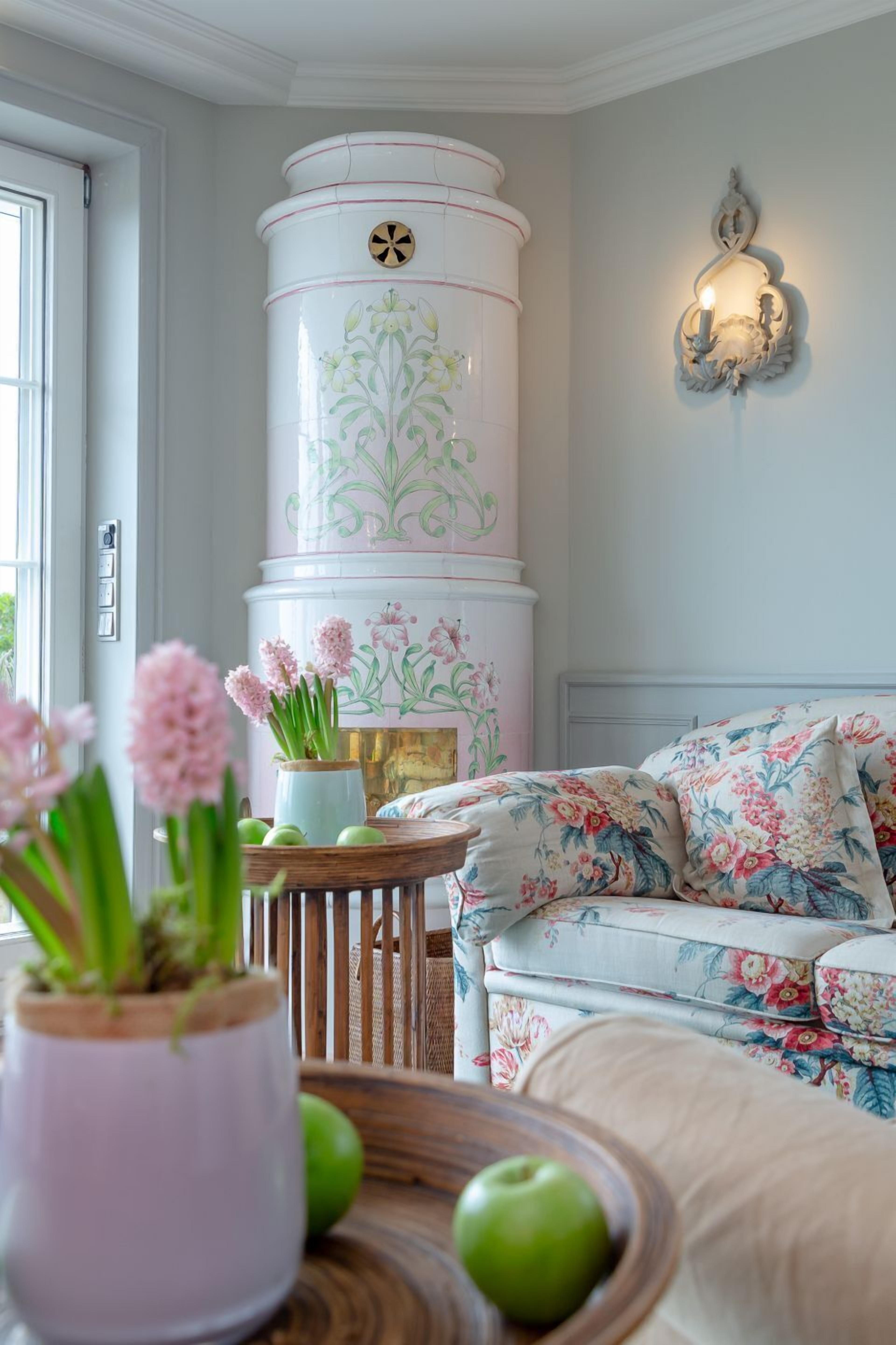 A living room with a white cylindrical object, floral cushions, and a wall-mounted light fixture.