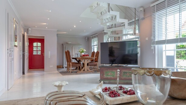 A modern living room with a dining area, a staircase, and a TV. - Rosen/horstweg 5 - Ferienhaus "rosen/horstweg 5" in Alt-westerland/tinnum (Sylt)