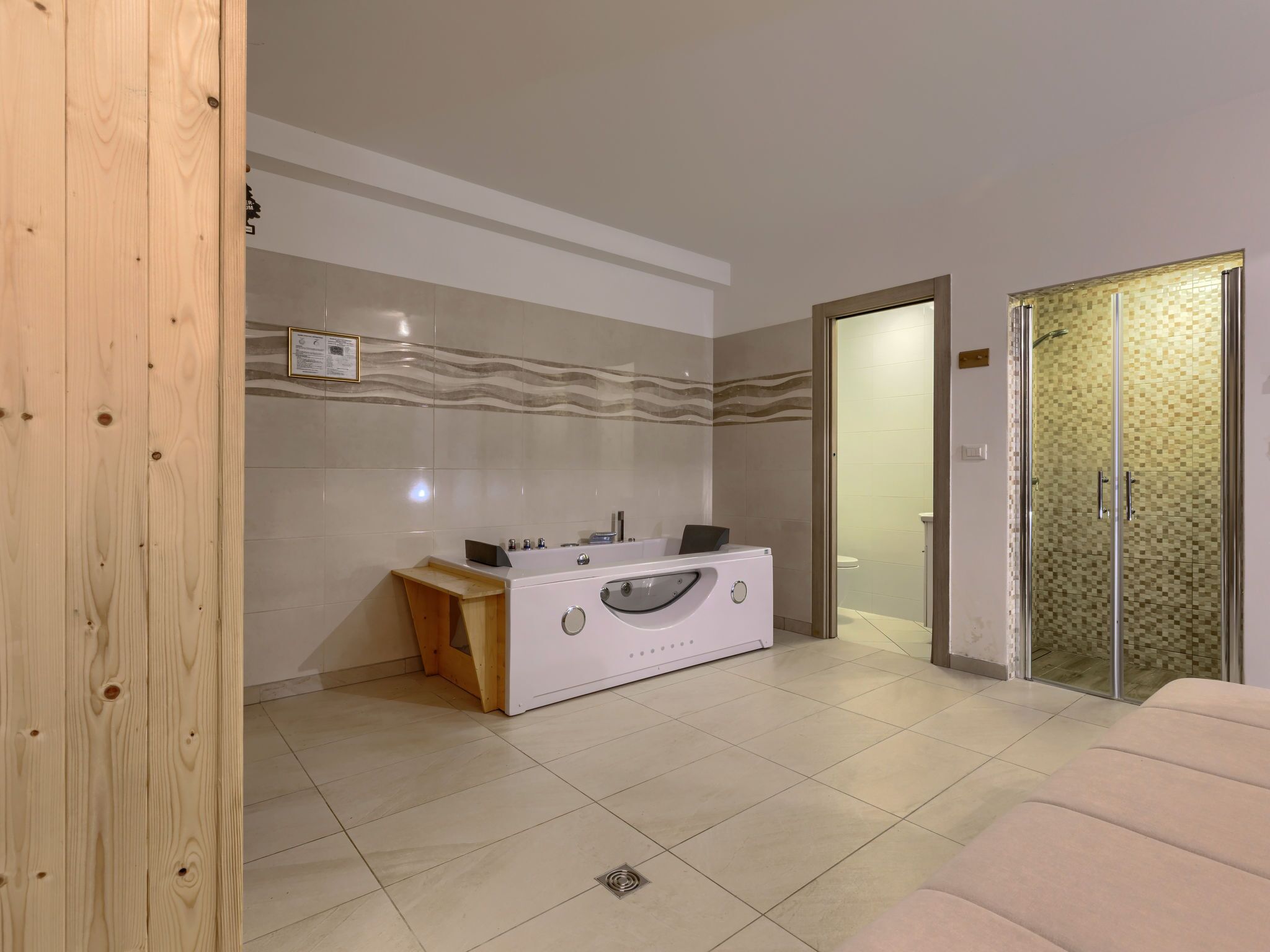 Et moderne badeværelse med et hvidt toiletbord, en bruseniche og en træbænk.