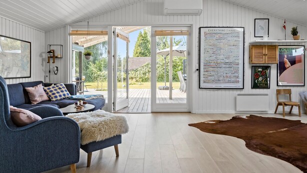 Un ampio soggiorno con un divano blu, un tavolino in legno e un'ampia porta vetrata che dà su un patio.