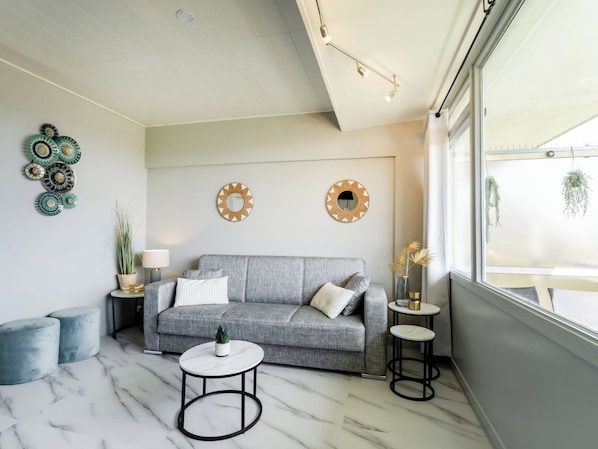 A living room with a grey sofa, a round coffee table, and decorative wall art.