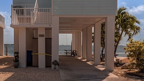 Una casa davant de la platja de dos pisos amb un balcó, un porxo cobert i vistes a l'oceà.