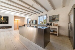 Eine moderne Küche mit einer zentralen Kochinsel, integrierten Geräten und einem großen Fenster für natürliches Licht.