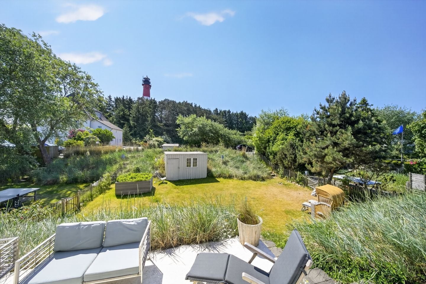 Un jardín con un cobertizo, un banco y una mesa.