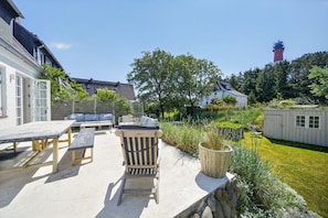 Eine Terrasse mit Gartenmöbeln, einem Holzstuhl und einem kleinen Schuppen.