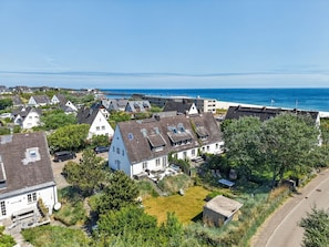 Ein Küstenwohngebiet mit Häusern, freiem Blick auf das Meer und einer asphaltierten Straße.