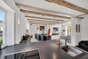 Une cuisine moderne dotée d’un îlot central, de luminaires suspendus et de poutres apparentes en bois.