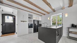 A modern kitchen with a central island, wooden beams, and a large window. - Lighthouse 4 - Exklusiv. Modern. Hochwertig. Strandnah (Hörnum (Sylt))
