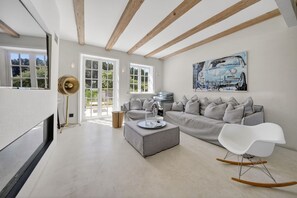Un salón moderno con un sofá gris, una silla blanca y un cuadro de un coche.
