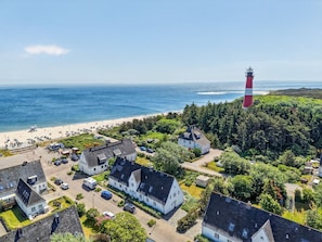 Eine Küstenstadt mit Leuchtturm, Strand und Wohnhäusern.