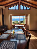 Un comedor con una mesa grande, sillas y vistas a montañas y un lago.