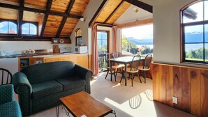 A cozy interior with a wooden ceiling, a dining area with a table and chairs, a sofa, and a kitchen area with a sink and cabinets. - Manapouri Holiday Park (Manapouri)
