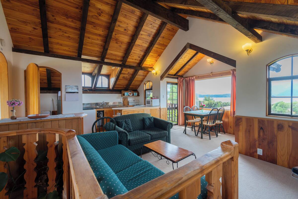 Un interior acogedor con techo de madera, un sofá, una mesa de comedor y una zona de cocina.