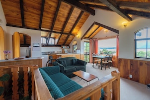 Un interior acogedor con techo de madera, un sofá, una mesa de comedor y una zona de cocina.