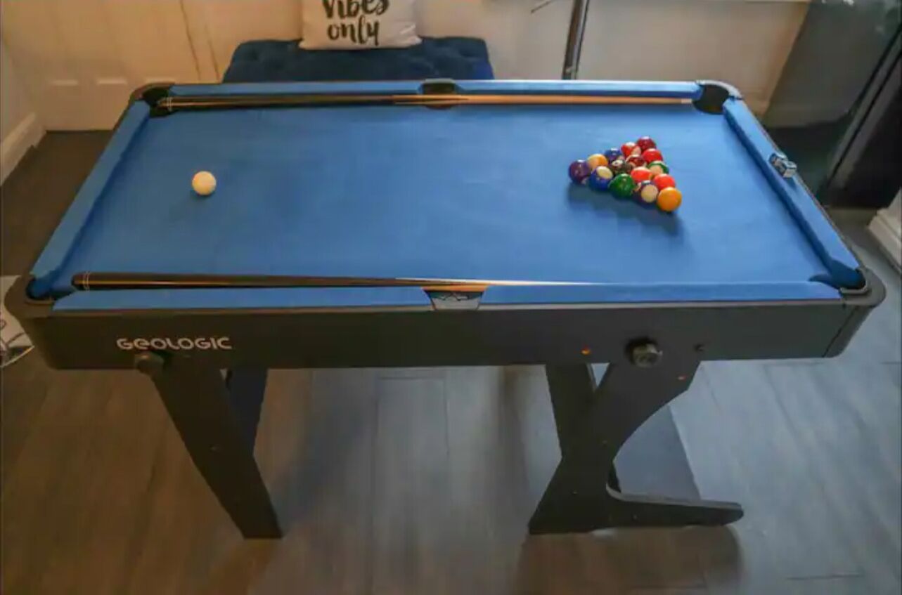 Ein Billardtisch mit Spielzeug und Queue.