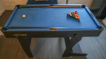 Ein Billardtisch mit Spielzeug und Queue.