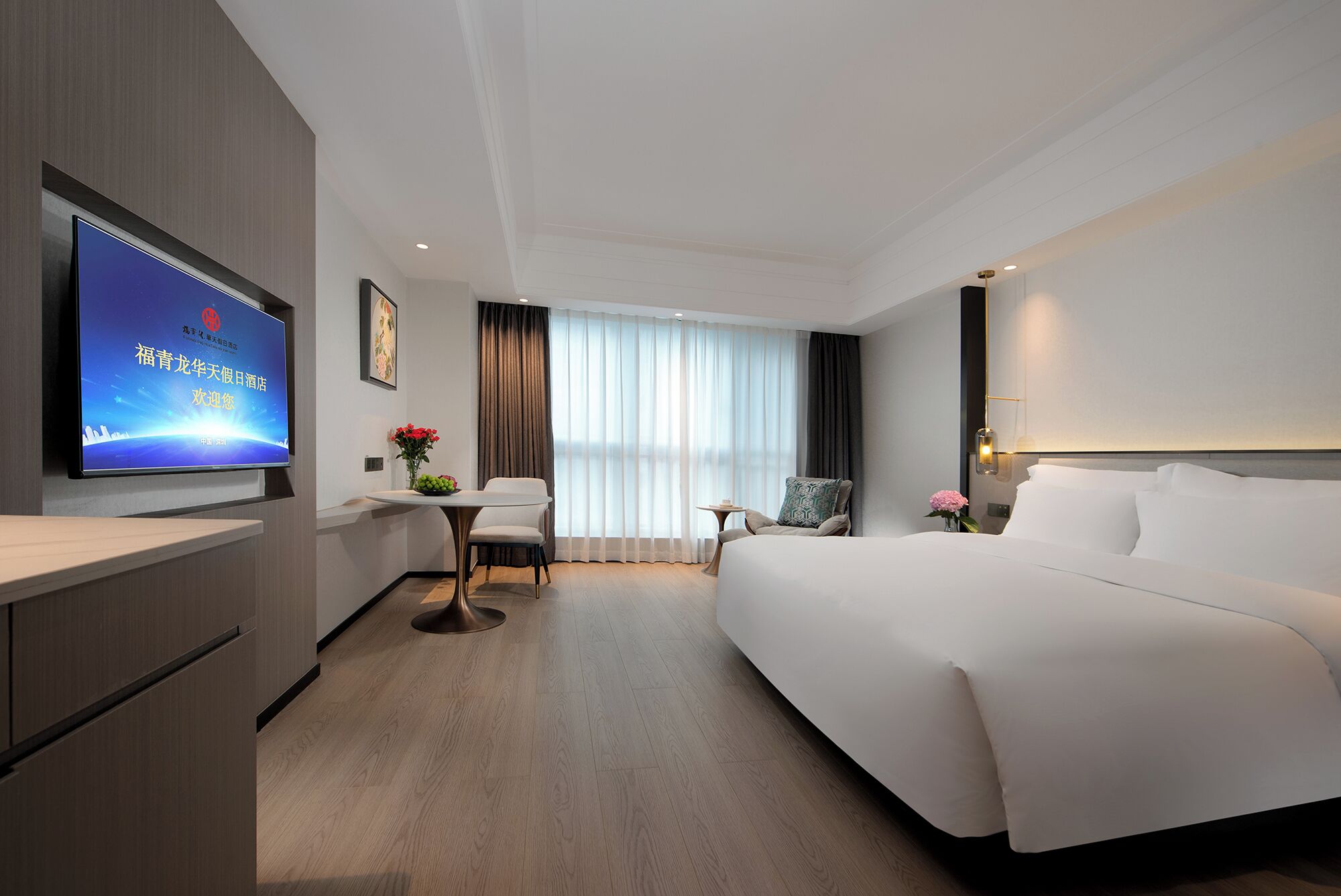 A hotel room with a bed, a desk, a chair, a TV, and a window with curtains.