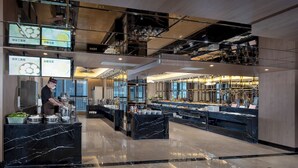 A modern hotel lobby with a marble floor, a buffet area, and a kitchen in the background. - Fuqinglong Huatian Holiday Hotel (Shenzhen)