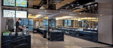 A modern hotel lobby with a marble floor, a buffet area, and a kitchen in the background.
