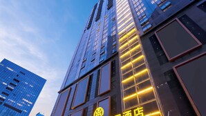 A modern hotel with a prominent sign in a foreign language, surrounded by other high-rise buildings. - Fuqinglong Huatian Holiday Hotel (Shenzhen)