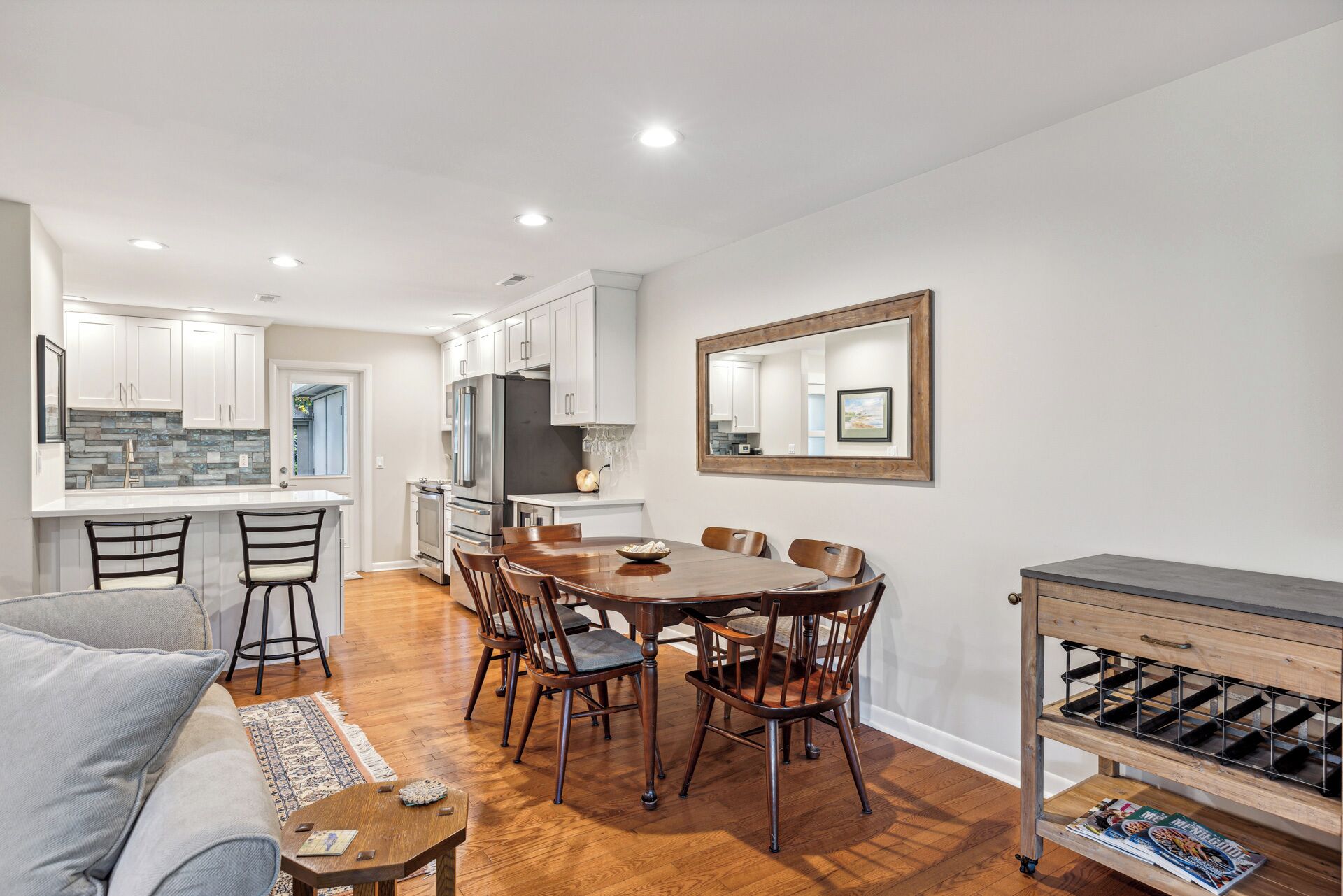 Una cocina moderna con armarios blancos, una isla grande y una zona de comedor con una mesa y sillas de madera.