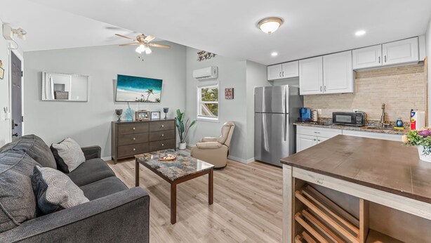 A modern kitchen with white cabinets, a stainless steel refrigerator, and a microwave.