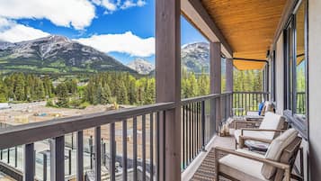 A balcony with a view of mountains, wooden furniture, and a construction site in the background.