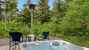 Een hottub met twee stoelen en een verwarming in een bebost gebied.
