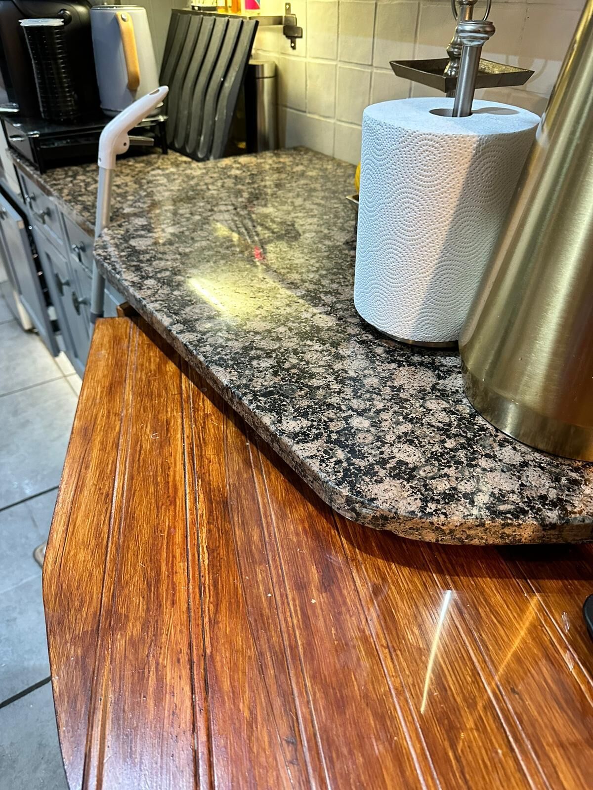 A kitchen counter with a granite top and a wooden section.