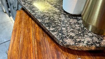 A kitchen counter with a granite top and a wooden section.