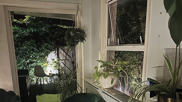 A modern kitchen with a marble countertop, a green chair, and potted plants. - My Sky Secret Garden Near atractions (London)