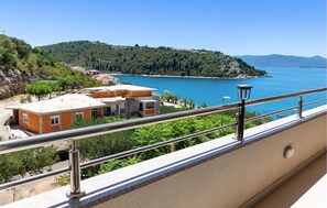 A balcony with a view of a coastal area, including buildings and a body of water.