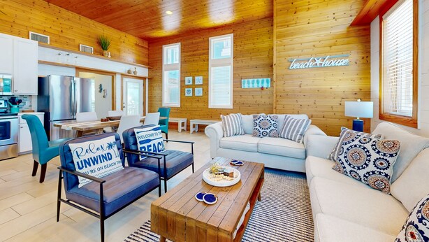 Een gezellig interieur van een chalet met houten plafond, een keukenhoek, een eethoek en een woonkamer met een bank en fauteuils.