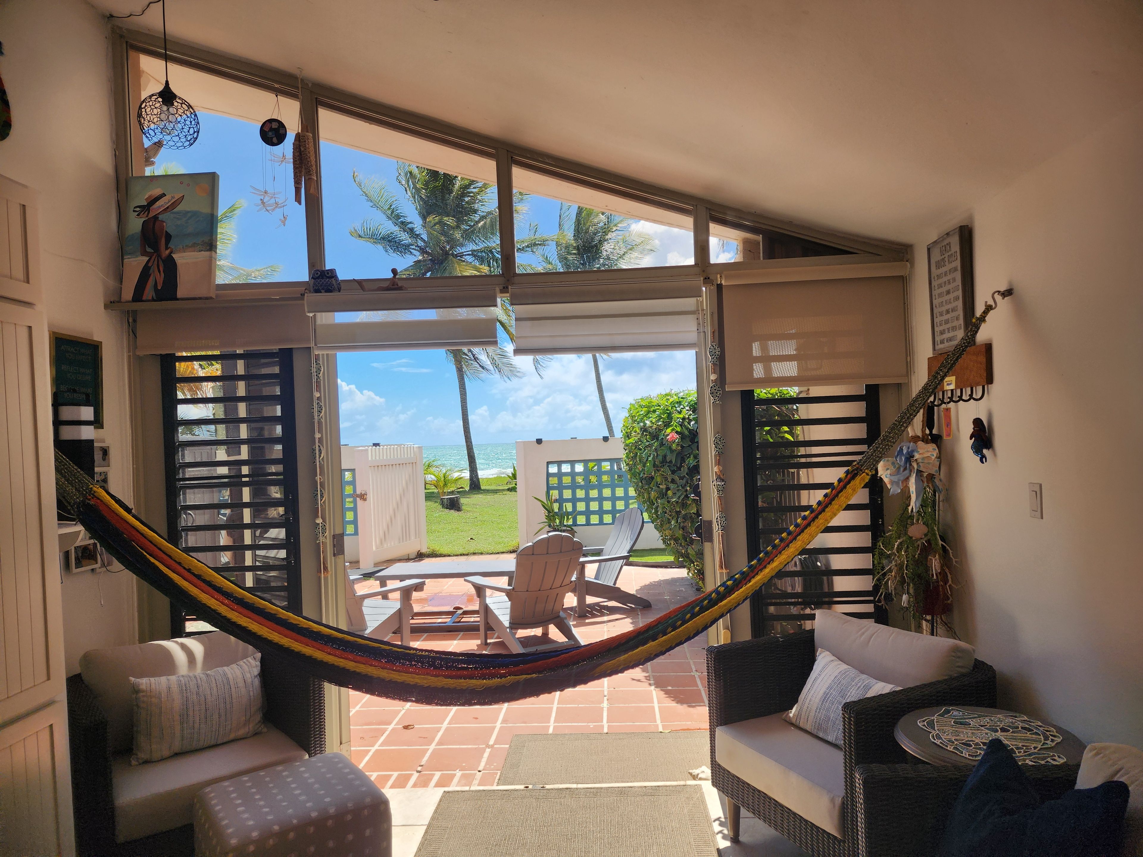 A room with a hammock, a sofa, and a view of the ocean.