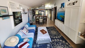 A living room with a sofa, a coffee table, and a television. There is a dining area with chairs and a table. - Ocean Breeze Villa. (Arroyo)