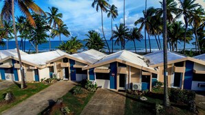 A row of beachside cabins with a view of the ocean and palm trees. - Ocean Breeze Villa. (Arroyo)