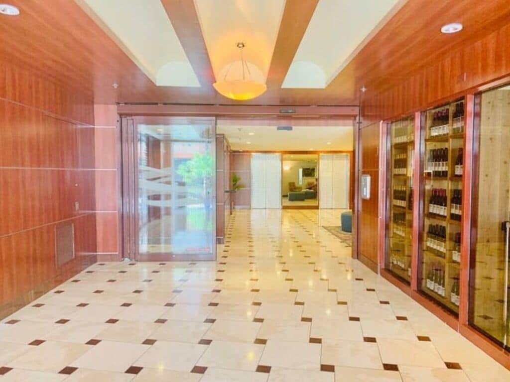Un hall d’hôtel avec un sol à carreaux, des lambris en bois et une porte vitrée donnant sur une autre pièce.