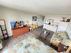 A compact living space with a television, wooden furniture, a kitchen area, and a patterned rug. - 🌟location🌟5min to 🏄‍♀️🏊‍♀️🐠🦈🌸🏖 ➕free 🚗🅿️➕💨WIFI🌺F13A10🌺 (Honolulu)