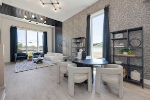 Un salon moderne avec une table à manger ronde, des chaises blanches, un canapé et une bibliothèque.