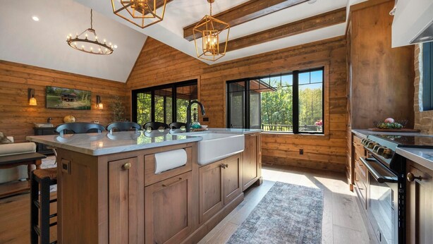 A spacious kitchen with wooden cabinetry, a large island, and a view of the outdoors. - Cedar Cove Cabin, Private Beach near Galena (Elizabeth)
