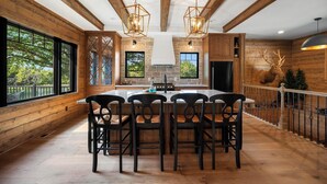 A spacious kitchen with a large island, wooden beams, and a stone fireplace. - Cedar Cove Cabin, Private Beach near Galena (Elizabeth)