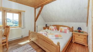 Un dormitorio con una cama de madera, una ventana con vistas, una silla y una mesita de noche.