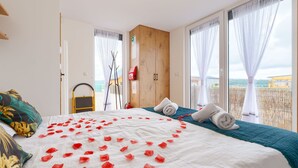 Una habitación de hotel con cama, armario de madera, ventana con vistas y balcón.