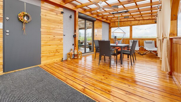 Un interior de madera con zona de comedor, ventilador de techo y vistas a través de un ventanal.