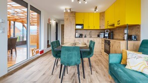 Una cocina moderna con armarios amarillos, un comedor con sillas verdes y un techo de madera.