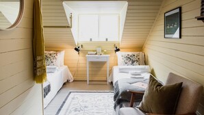 A cozy, well-lit attic bedroom with two beds, a small desk, and a chair. - Fjærland Fjordstove Hotell (Sogndal)